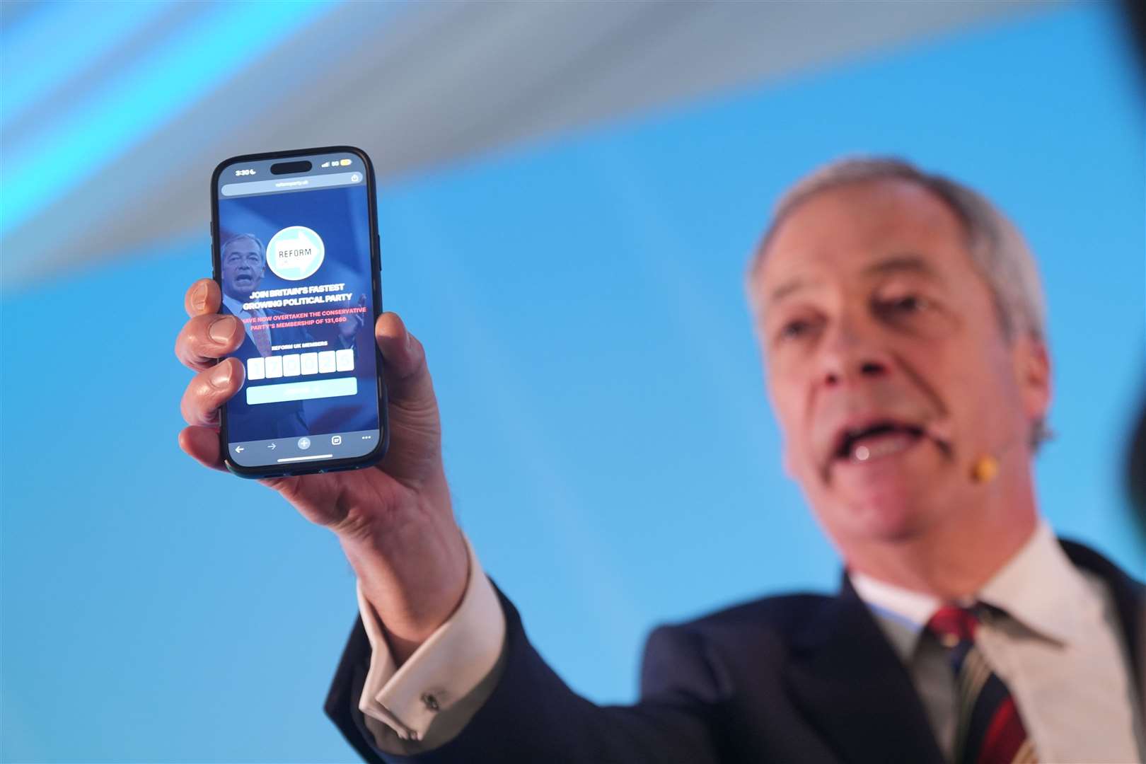 Reform UK leader Nigel Farage holding a phone displaying the number of Reform UK party members (Yui Mok/PA)