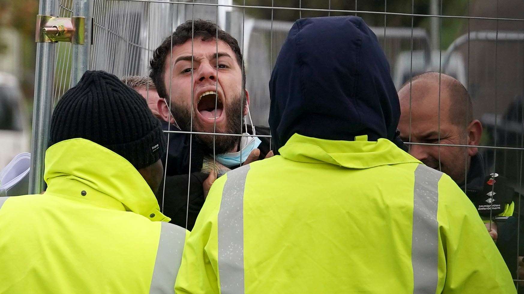 A migrant attempting to communicate with journalists at the Manston immigration short-term holding facility (Gareth Fuller/PA)