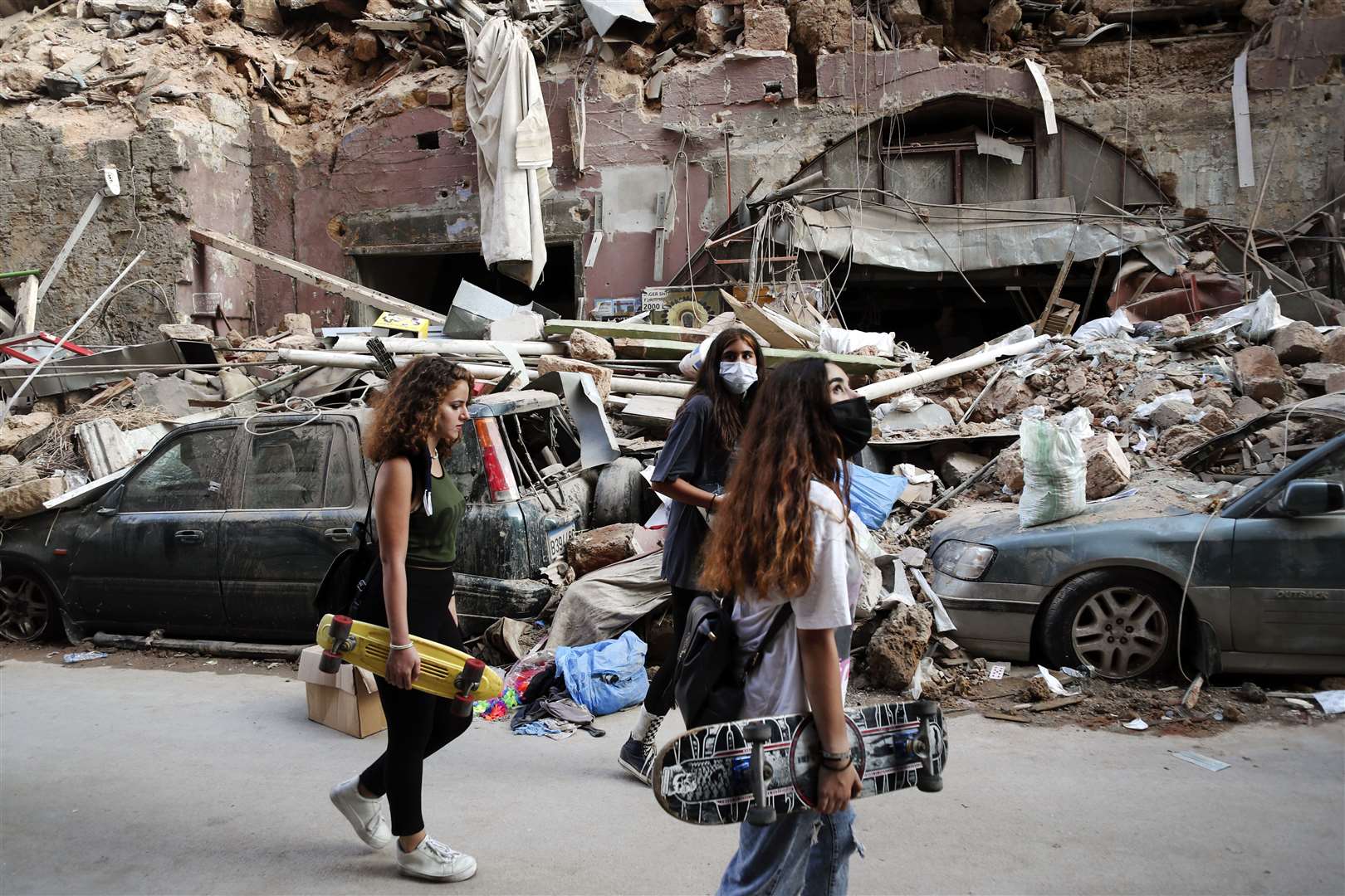 Women walk past destroyed cars in a neighbourhood near the scene of Tuesday’s explosion in Beirut (Thibault Camus/AP)