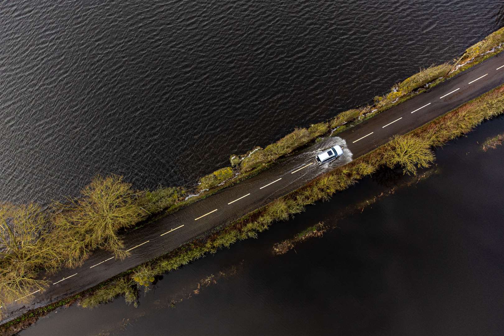 A car drives through floodwater near Muchelney, Somerset (Ben Birchall/PA)