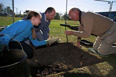 Caitlin Doyle, 12, Nicholas Doyle, and John French look at a piece of bone that has been found in their part of the dig.