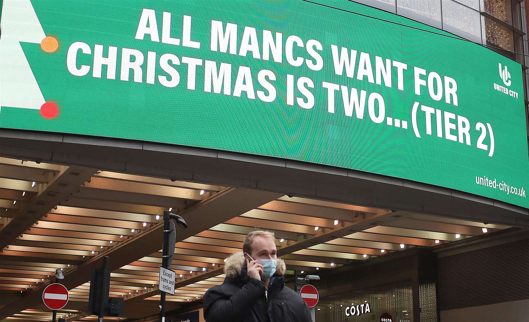 A man wearing a face mask walks past a sign on Market Street, Manchester (Martin Rickett/PA)