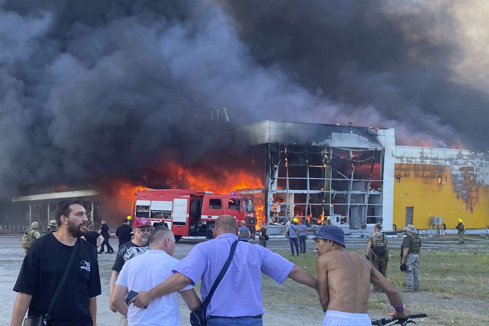 People watch as smoke bellows after a Russian missile strike hit a crowded shopping mall in Kremenchuk (Viacheslav Priadko/AP)