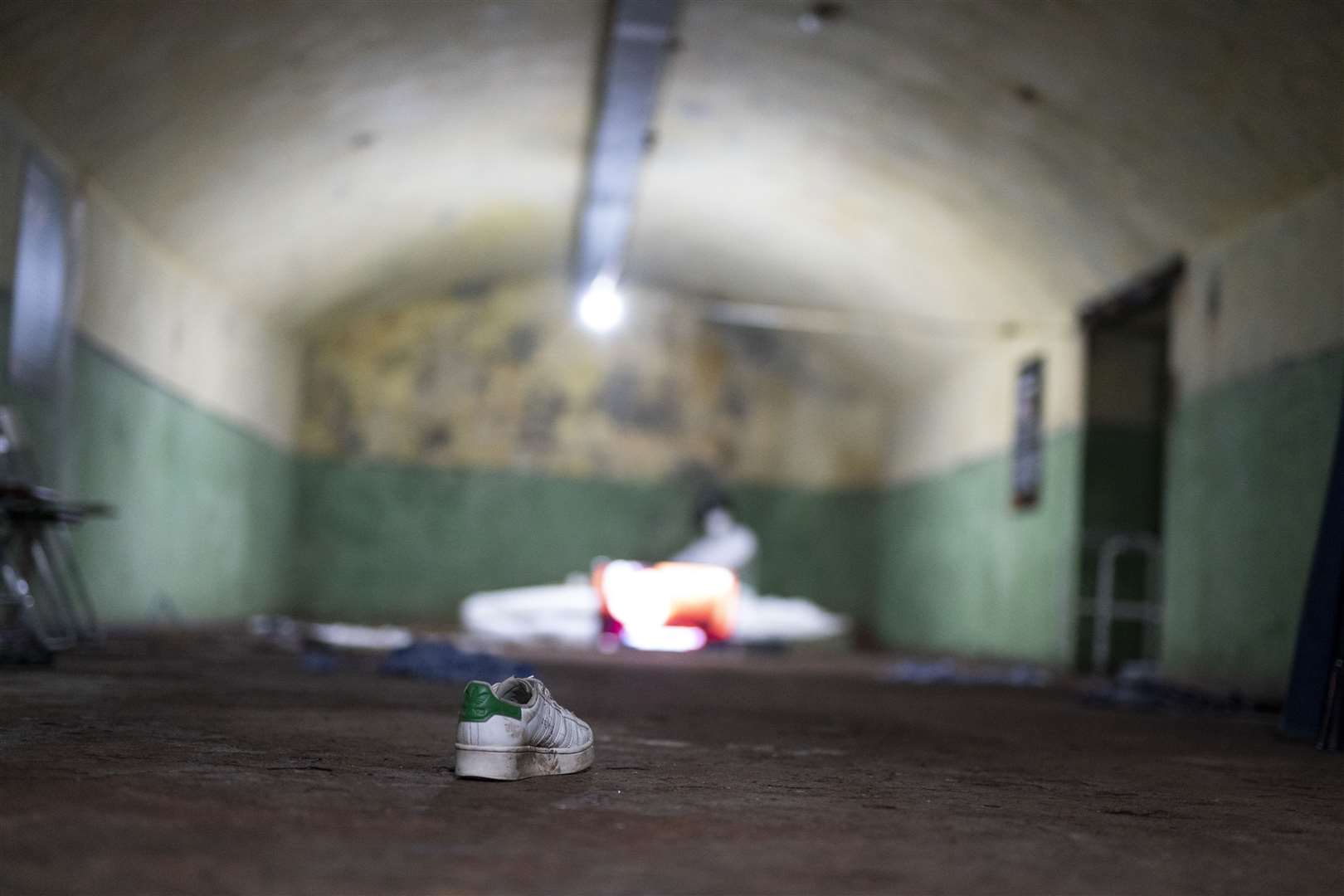 The underground rooms in the exhibition are dimly lit with items of clothing strewn over the floor (Jordan Pettitt/PA)