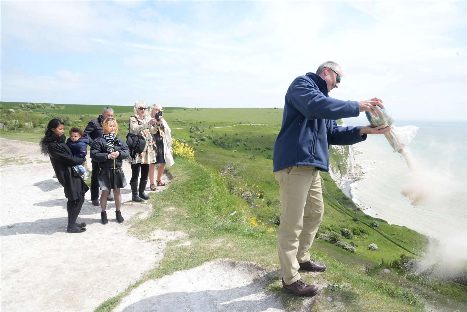 Craig Reynolds scattering of the ashes of his father. He is on a sloped step away from the cliff edge.