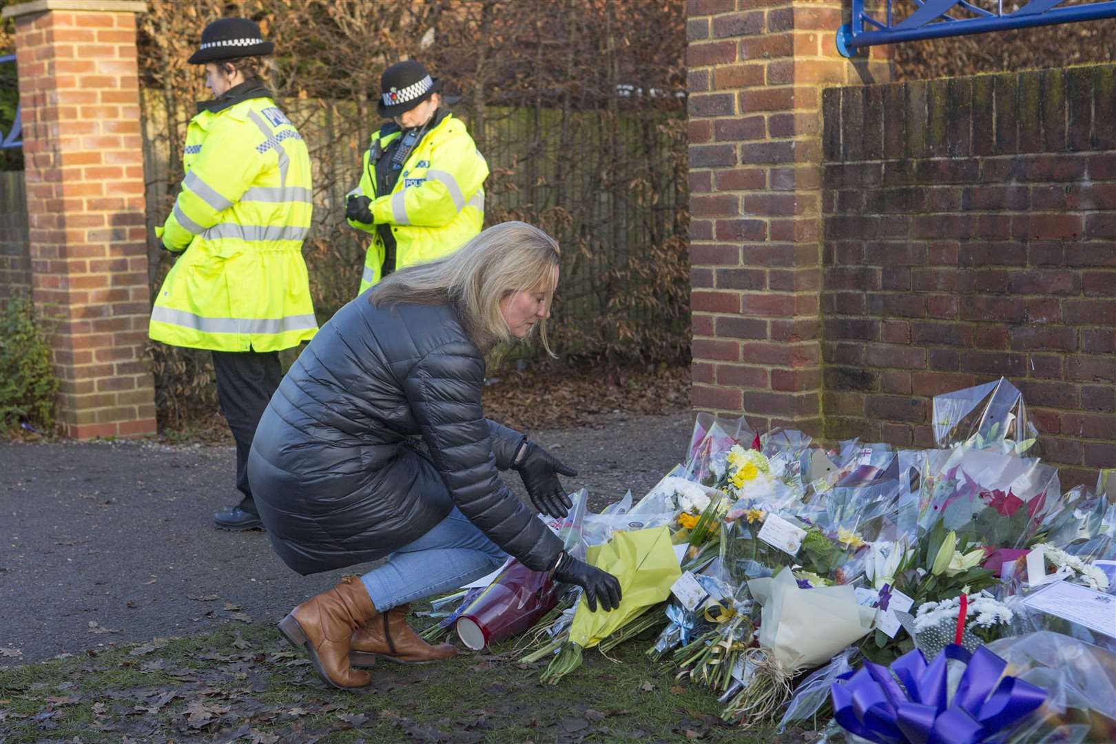 A woman leaves a floral bouquet at the entrance to Debden Park High School in Loughton (Rick Findler/PA)