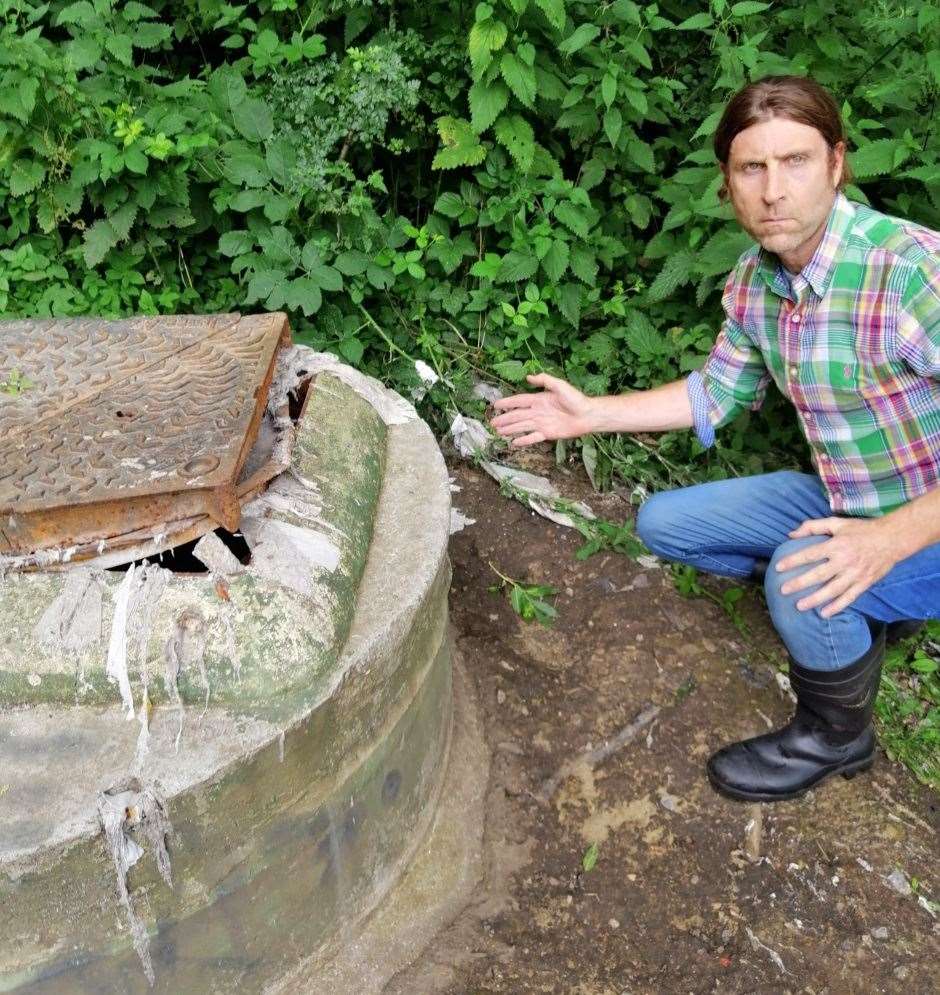 Cllr Harwood with one of the oozing manhole covers before the fix