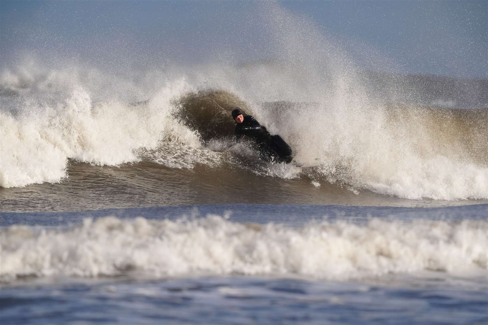 A surfer in the sea at Tynemouth Longsands (Owen Humphreys/PA)