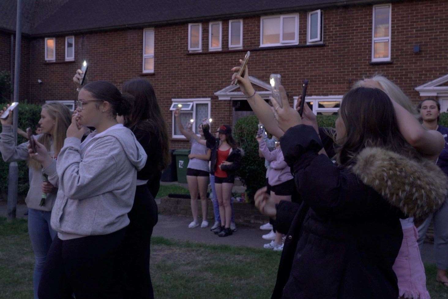 People holding phones up with torches on