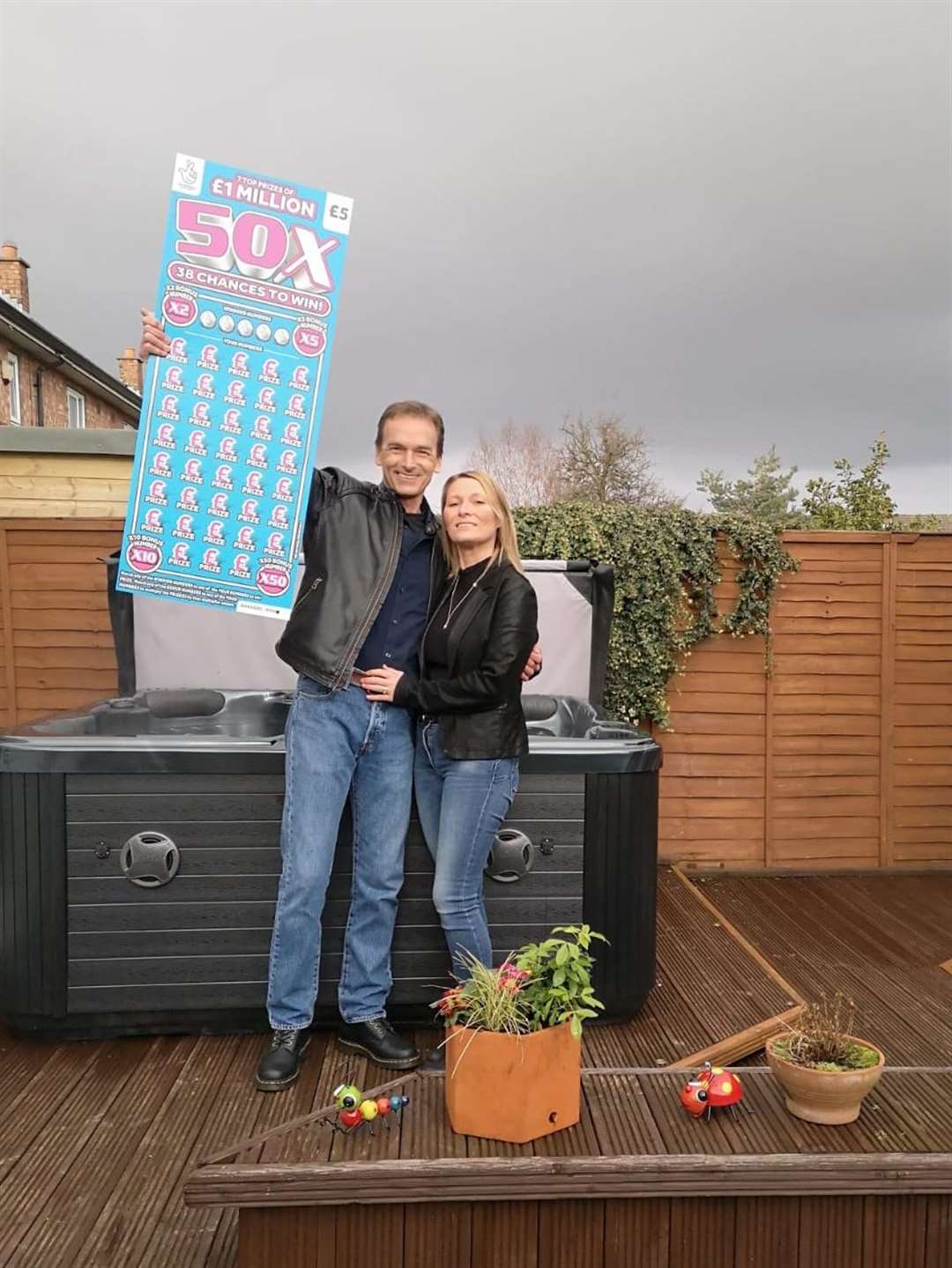 Mark Plowright with his wife Sara and their new hot tub (National Lottery/PA)