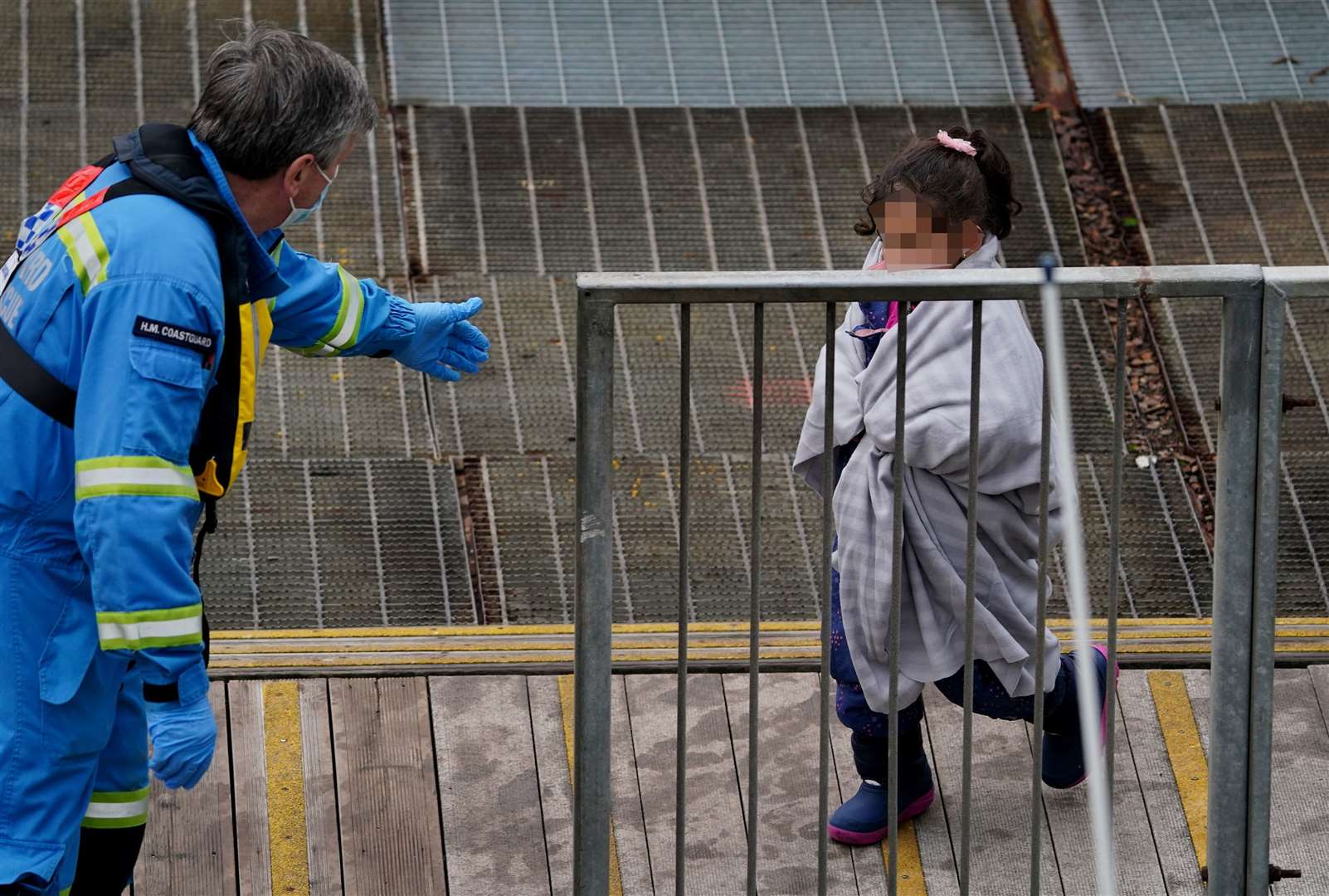 A young girl is helped by a Coastguard officer as she arrives in Dover (Gareth Fuller/PA)