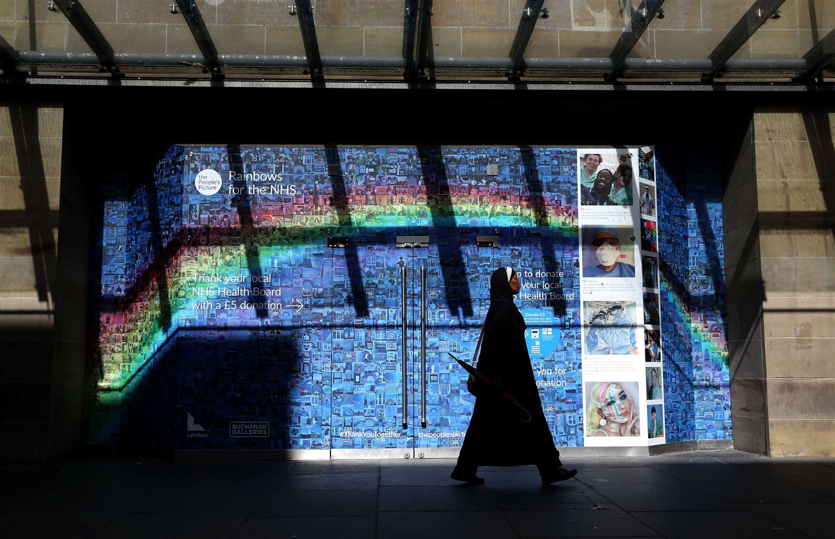 A woman walks past a Rainbows for the NHS mosaic made up of pictures and stories submitted during the pandemic at Glasgow’s Buchanan Galleries (Andrew Milligan/PA)