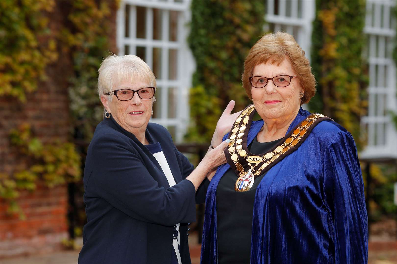 Pam Bates helps new Mayor Jill Anderson with her chain