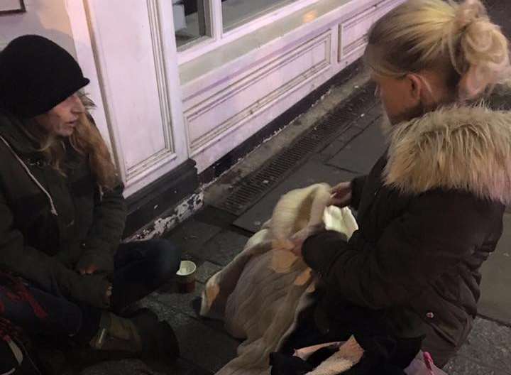 Naomi McMaster hands out goods to a homeless woman
