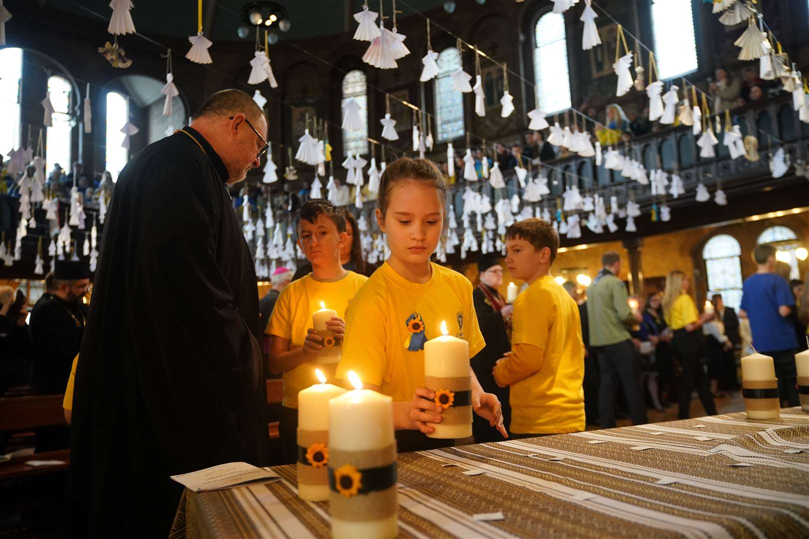 Children from St Mary’s Ukrainian School lighting some of the 52 candles – one for each week of the war (Yui Mok/PA)