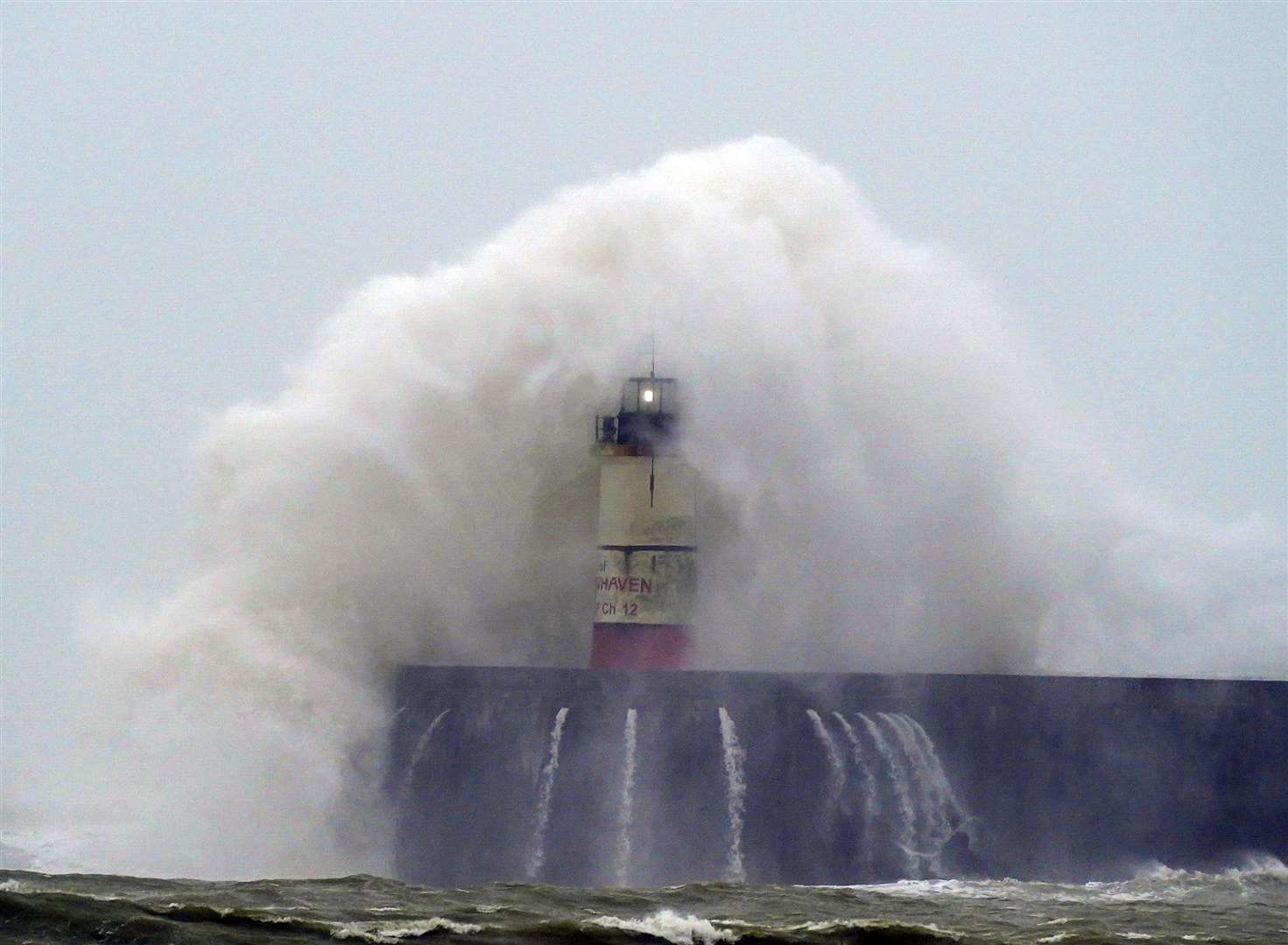 A wave crashes over Newhaven lighthouse at West Quay in East Sussex (Steve Parsons/PA). 