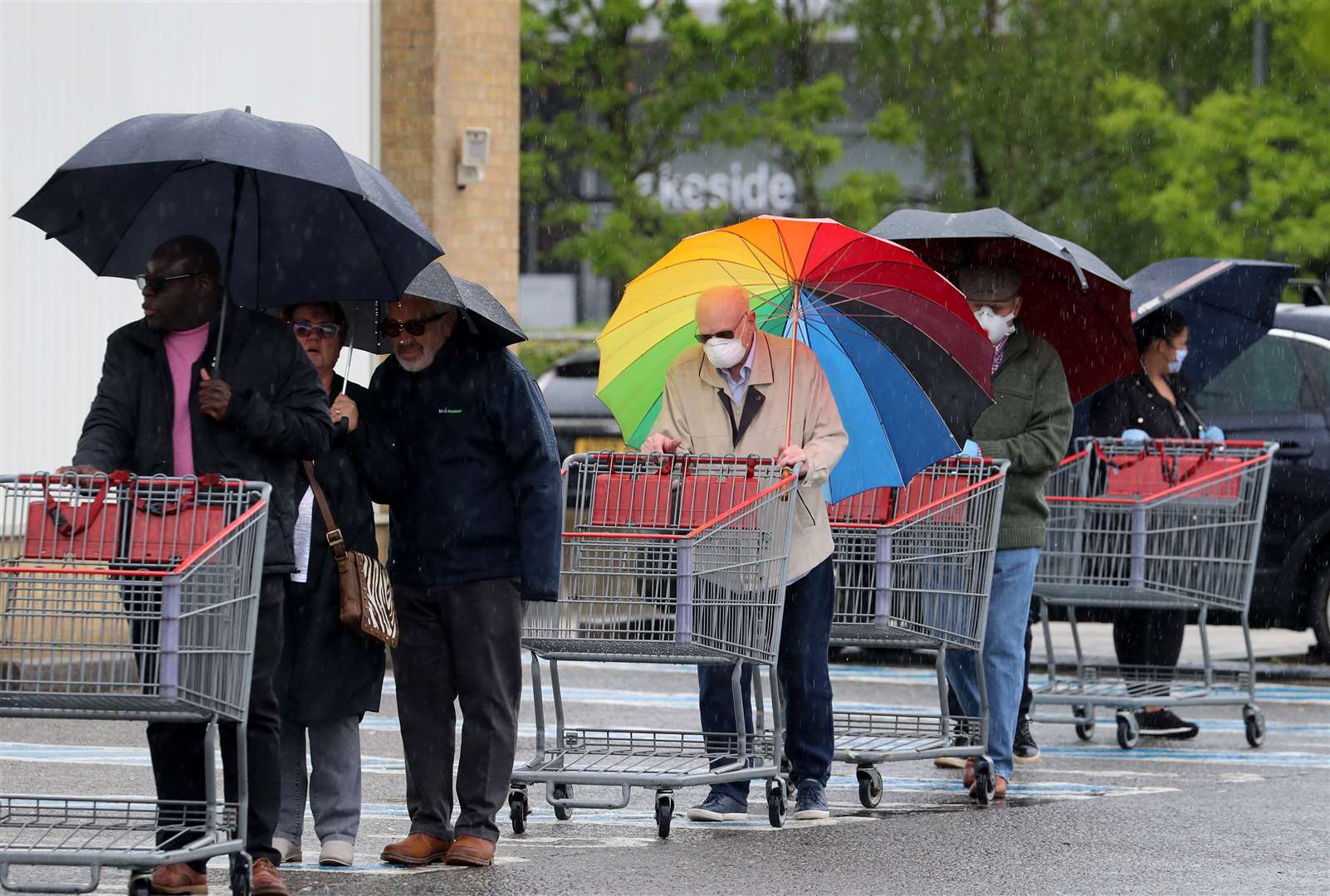 A shopper outside Costco in Thurrock carried a rainbow umbrella during Tuesday’s silence for fallen key workers (Gareth Fuller/PA)