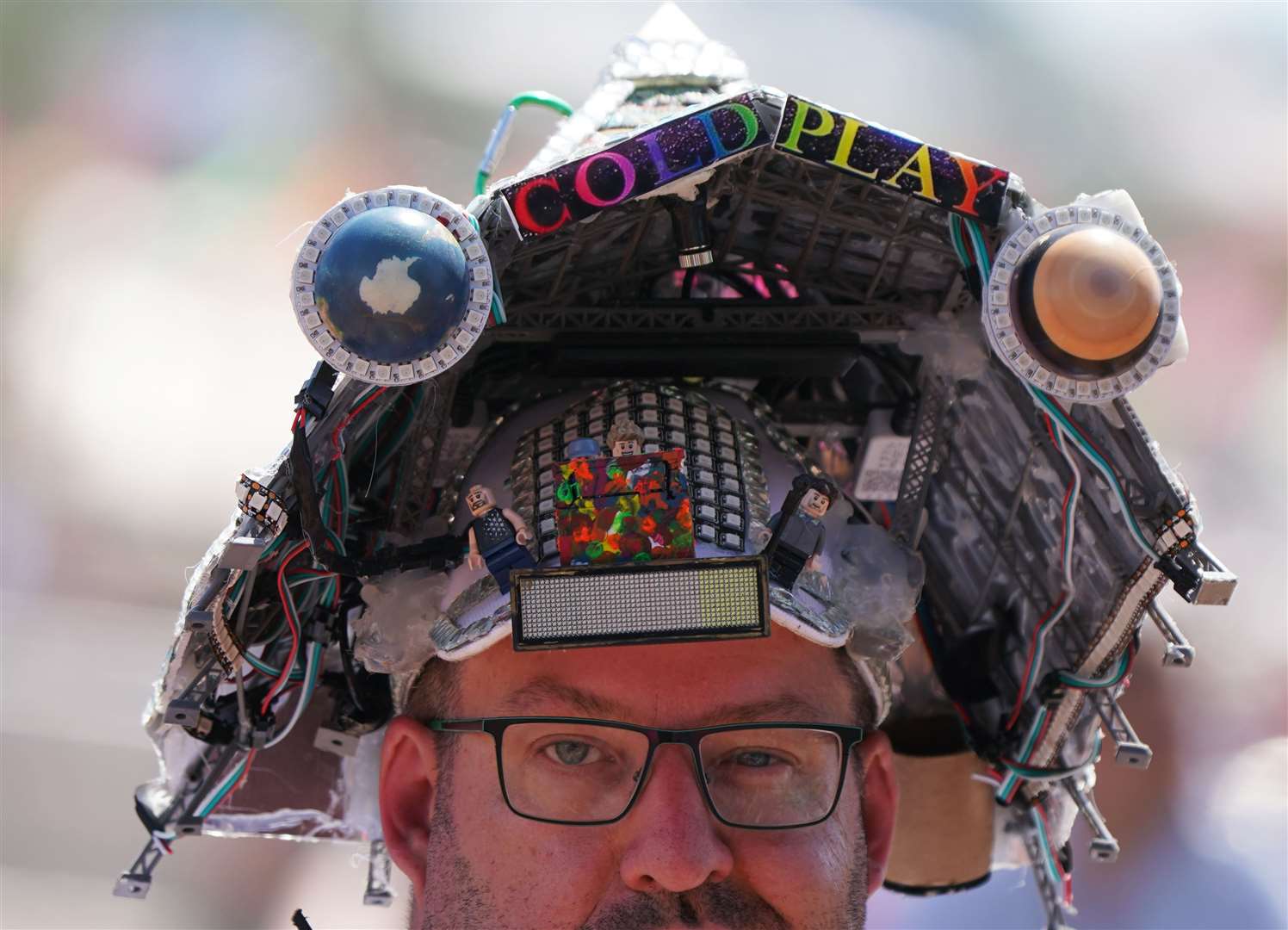 A festivalgoer wearing a Pyramid Stage Coldplay hat at the Glastonbury Festival at Worthy Farm in Somerset (Yui Mok/PA)