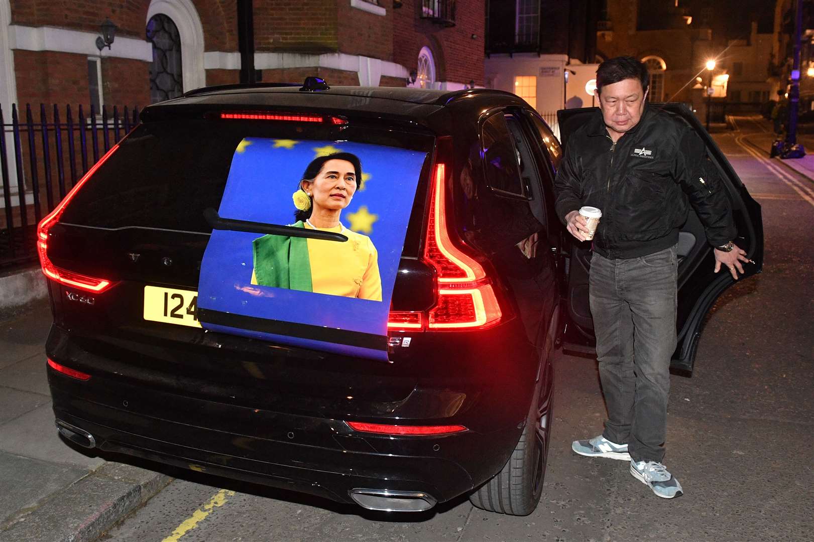 Kyaw Zwar Minn next to a car bearing Aung San Suu Kyi’s image (Dominic Lipinski/PA)