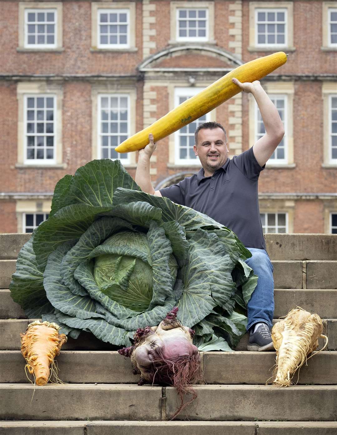 Paul Proud with his winning giant cabbage, parsnip, carrot, beetroot and cucumber following the giant vegetable competition at the Harrogate Autumn Flower Show at Newby Hall and Gardens near Ripon (Danny Lawson/PA)